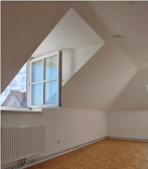 Dachgeschosswohnung mit Schrägfenster und Heizkörper in einem Neubau in Österreich.